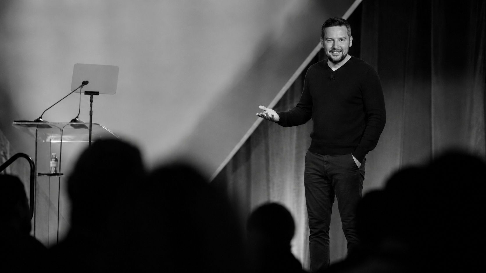 Franck Brunet speaking on stage, black-and-white photograph.